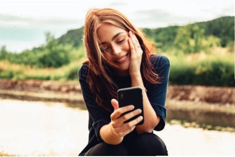 Cô gái đang nhắn tin cho chàng trai với nụ cười trên môi