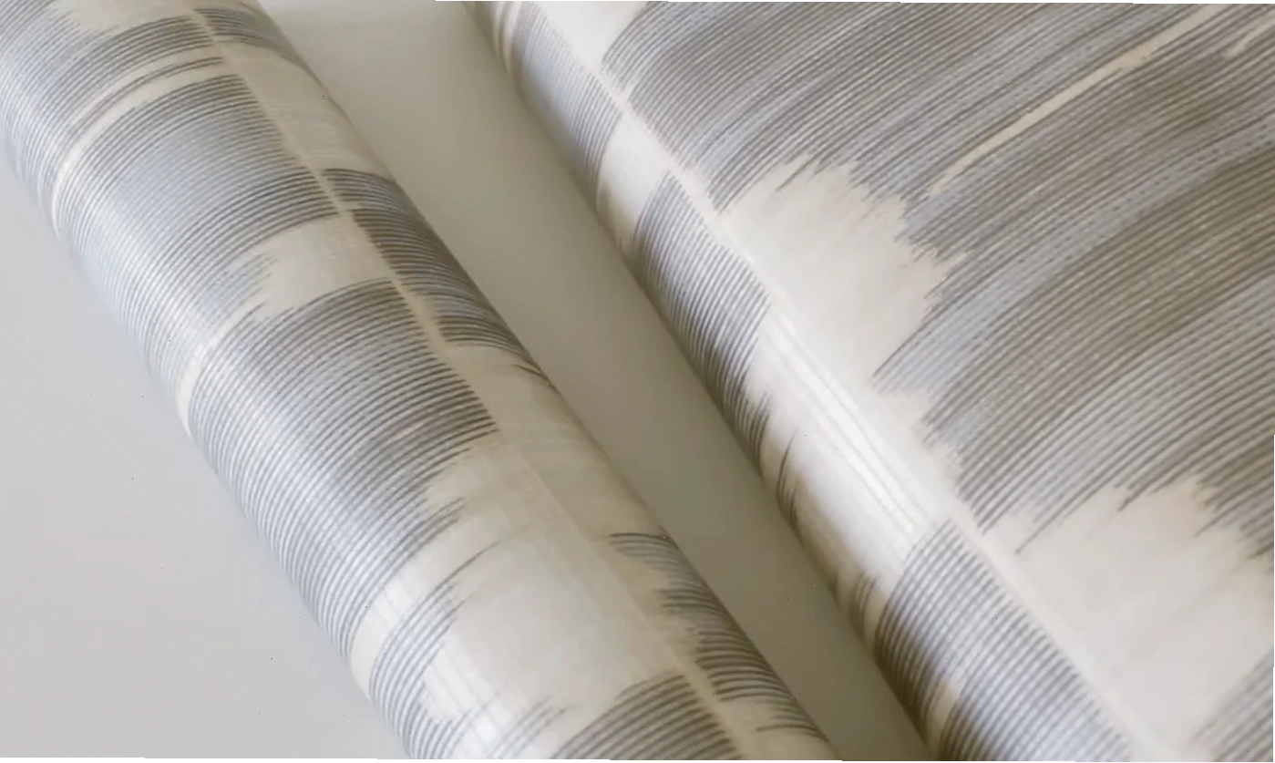 Two rolls of modern abstract wallpaper on a light surface